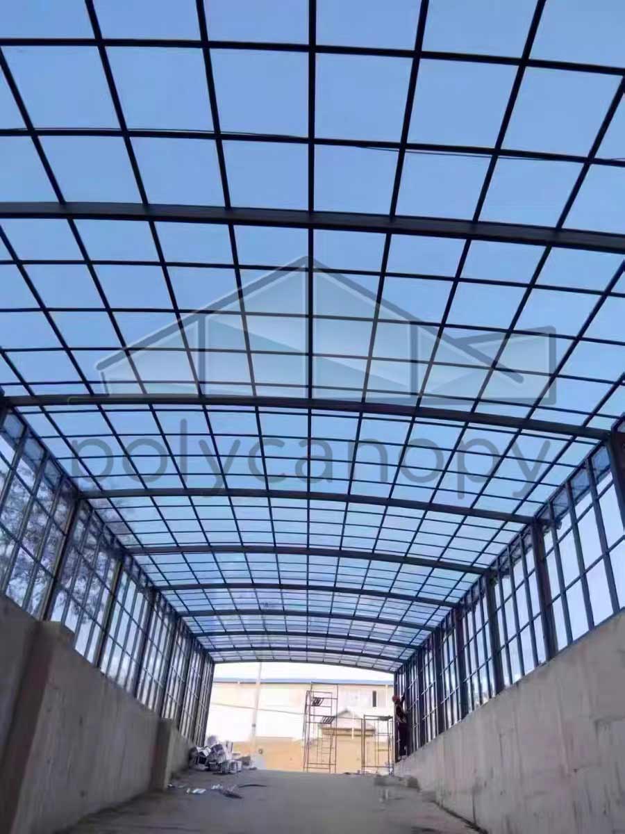 Massive polycarbonate canopy structure installed at a parking lot exit, offering strong coverage and modern design