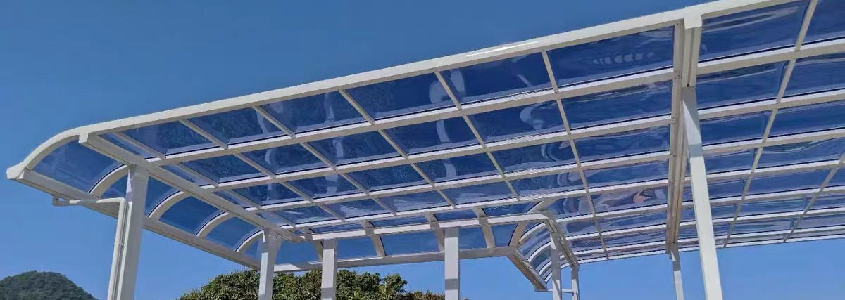 Blue polycarbonate canopy with white aluminum frame installed outdoors under a bright blue sky